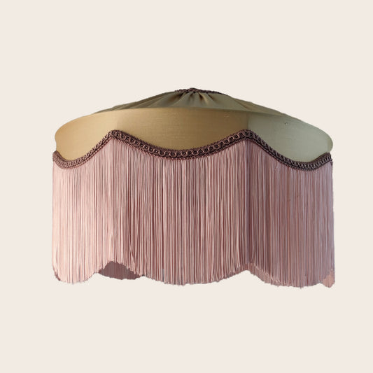 Decorative lampshade with a beige gold silk top and pink fringe.