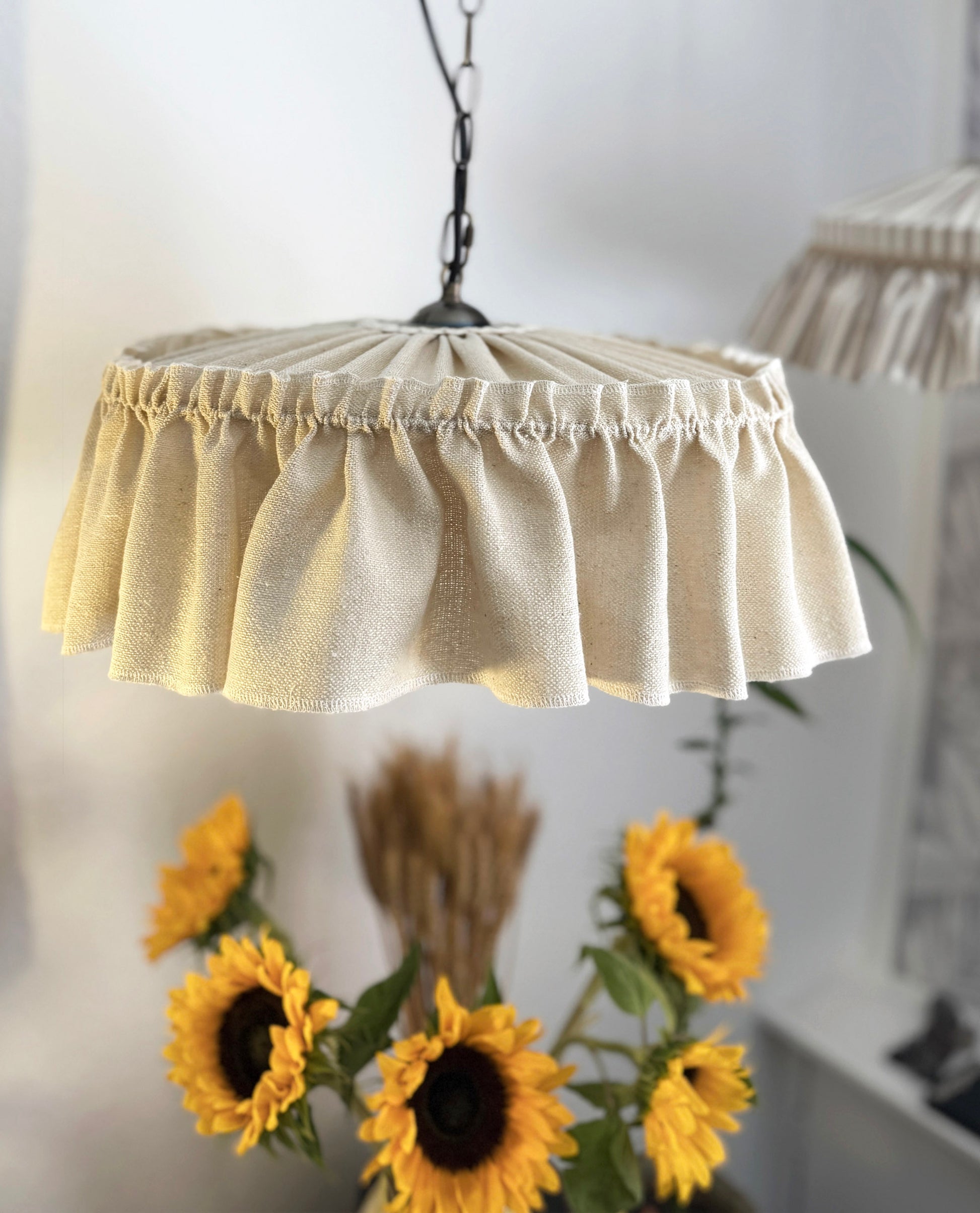 Pendant light with a ruffled beige shade in a home setting.