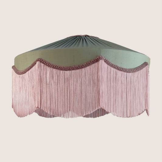 Decorative lampshade with green top and pink fringe on a beige background