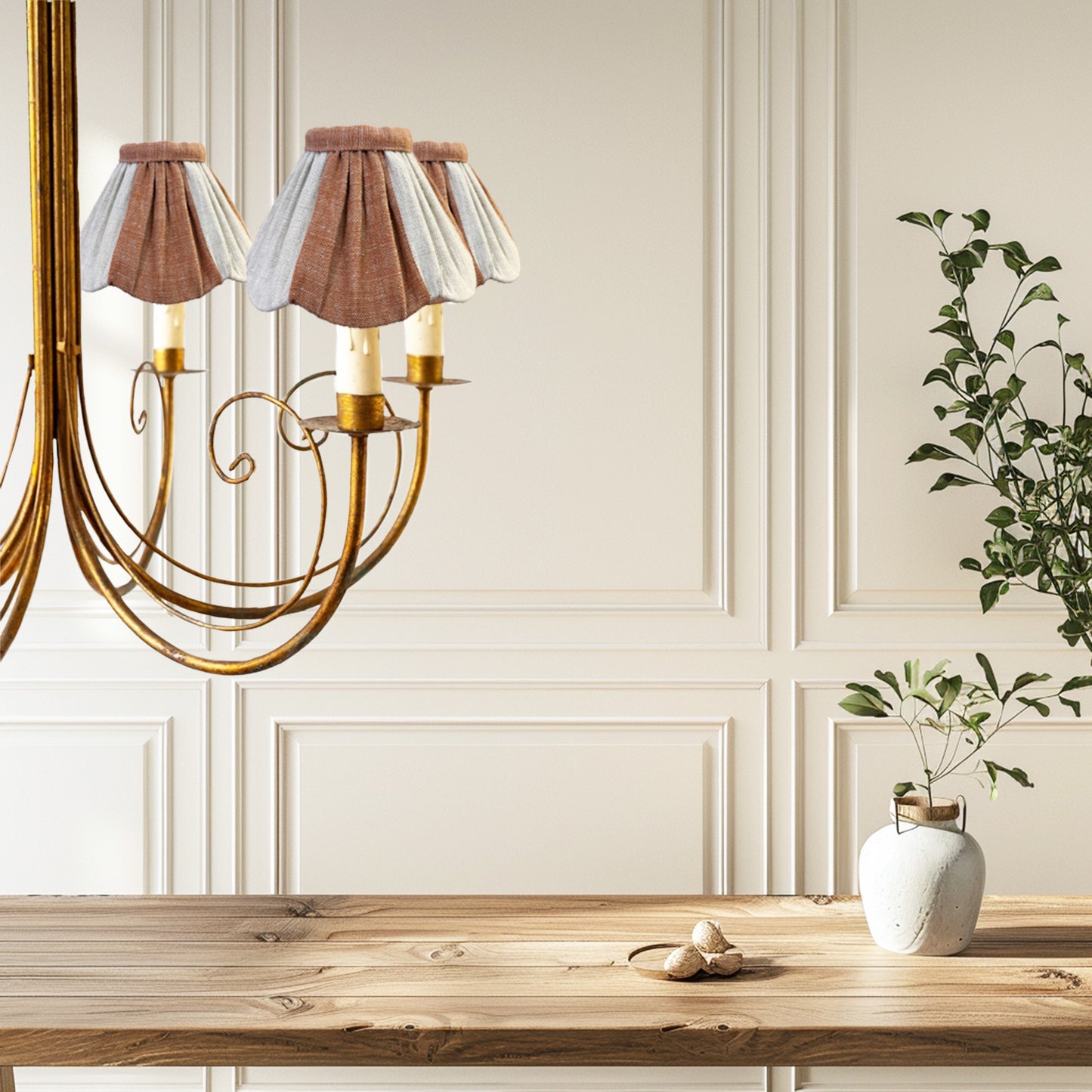 Chandelier with decorative lampshades in a room with wooden table and plants.
