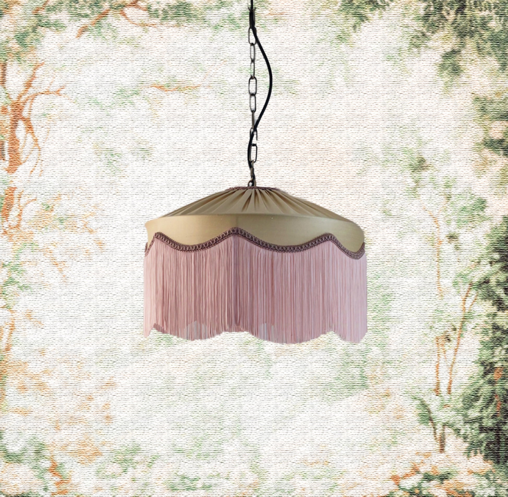 Decorative hanging beige gold silk lamp with pink fringe against a nature-themed background