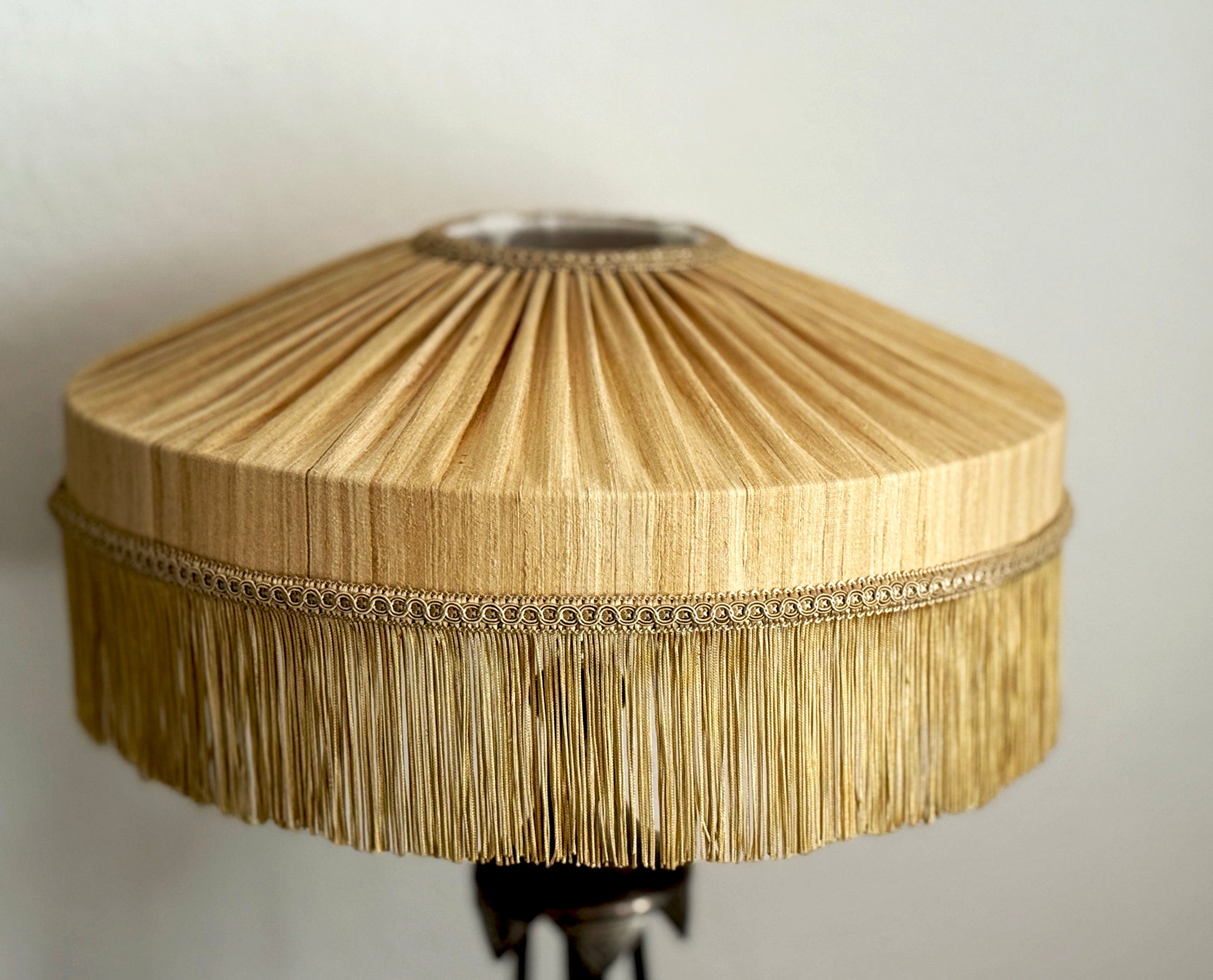 Close-up of a wooden lampshade with pleated design on a plain background
